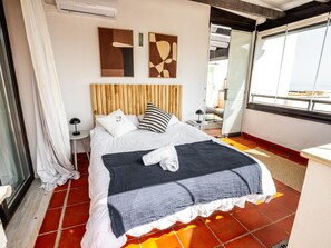 A hotel room with a bed, two wall art pieces, a window, and a door. - Penthouse with sea view, 6 guests (Casares)