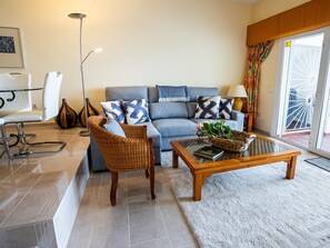 Un salon moderne comprenant un canapé, deux fauteuils, une table basse et un lampadaire.
