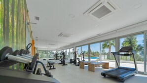 A gym with exercise equipment, large windows, and a view of a swimming pool. - Modern apartment with terrace - ? guests (Mijas)