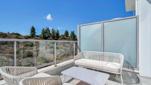 A balcony with white wicker furniture, a glass railing, and a view of a hilly landscape. - Modern apartment with terrace - ? guests (Mijas)