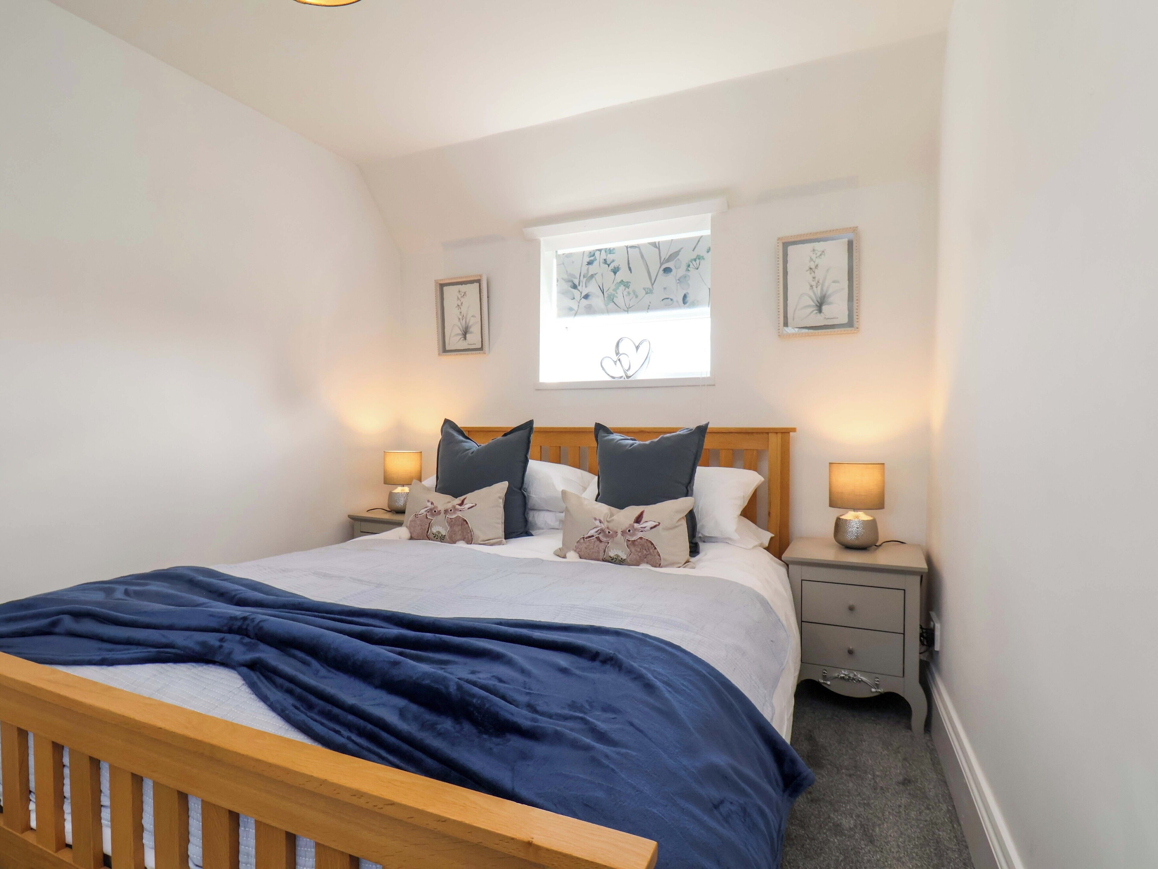 A bedroom with a bed, two bedside tables, a window with a view, and wall art.