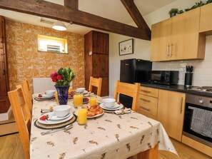 Un coin repas avec une table mise pour le petit-déjeuner, un réfrigérateur, un four à micro-ondes et un évier dans la cuisine.