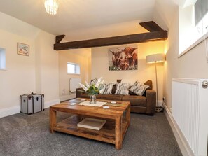 A cozy living room with a wooden coffee table, a brown sofa, a framed animal picture, and a radiator. - Lamb Cottage (Billingham)