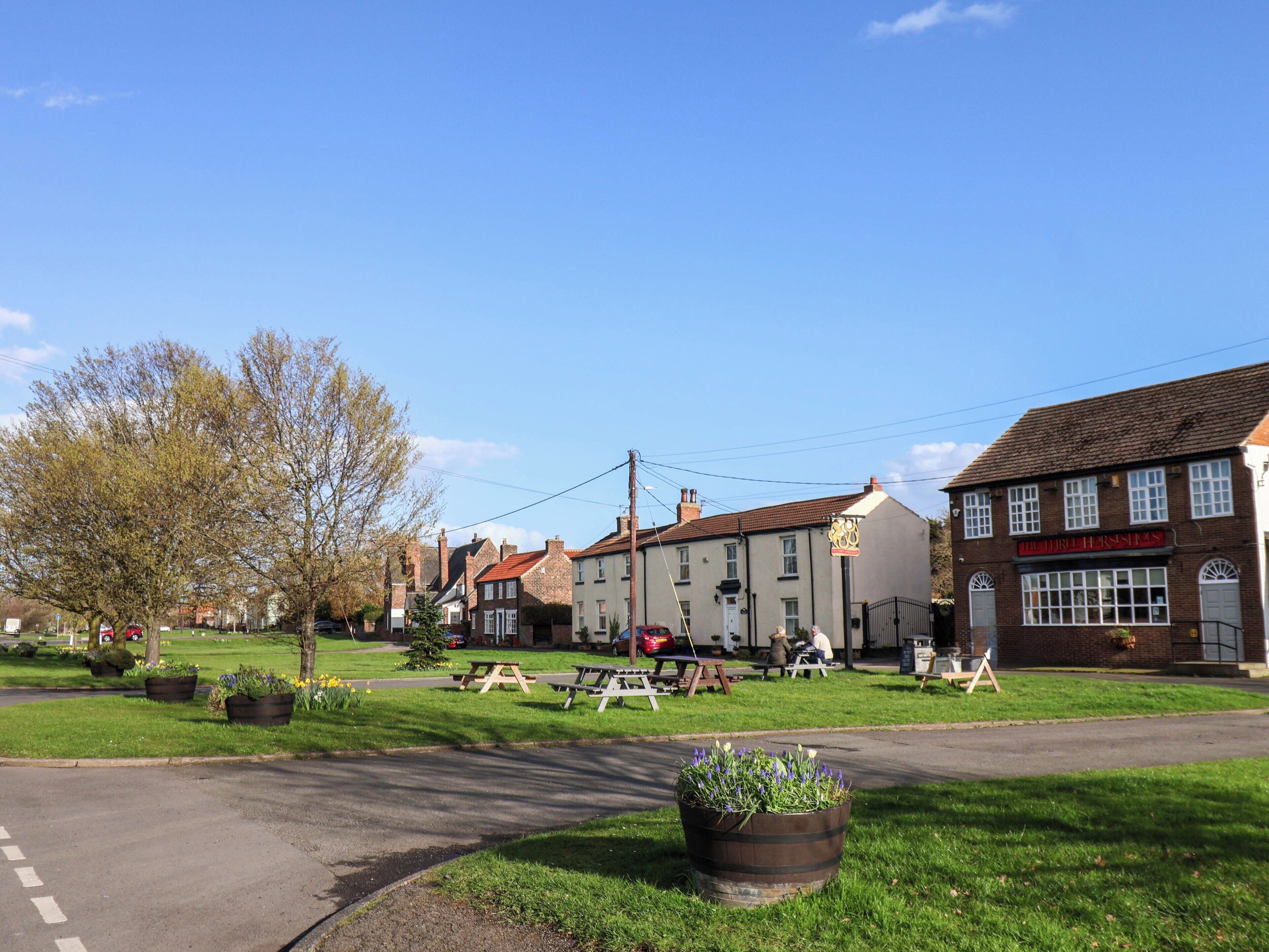 A traditional British pub with outdoor seating, surrounded by residential buildings.