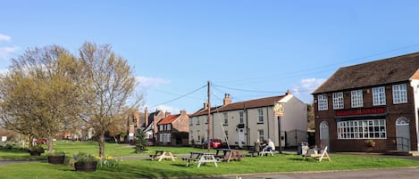 A traditional British pub with outdoor seating, surrounded by residential buildings.