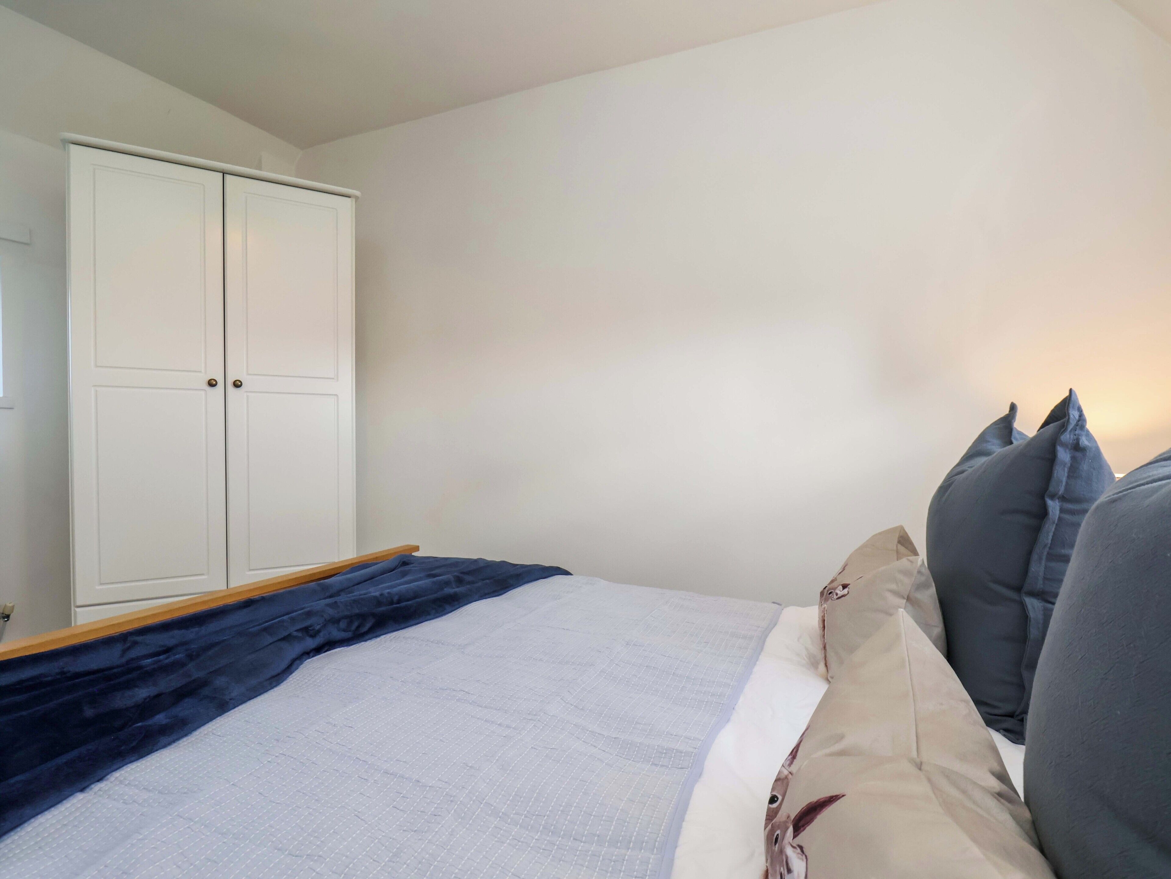 Une chambre à coucher avec un lit, une armoire et une table de chevet.