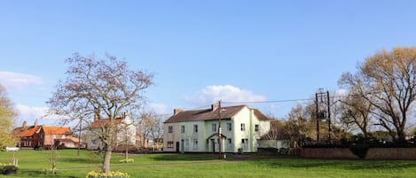 A residential area with a large house, a lawn, and a street.
