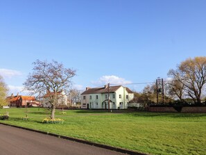 A residential area with a large house, a lawn, and a street. - Lamb Cottage (Billingham)