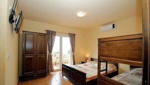 A bedroom with two wooden beds, a wardrobe, and a television.