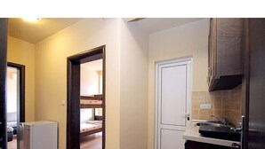 A compact kitchen with a refrigerator, a sink, and cabinets.