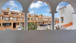 Een woongebied met meerdere appartementencomplexen, een wit gebouw met een rode dakbedekking en een balkon met bogen.