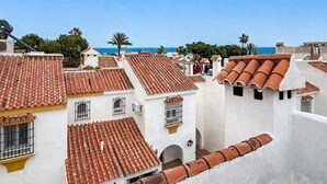 Een kustplaats met terracotta dakpannen, witte muren en een helderblauwe lucht.