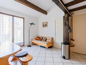 Ein gemütliches Zimmer mit einem Holztisch, einer Couch, einer Stehlampe und einem Mülleimer.