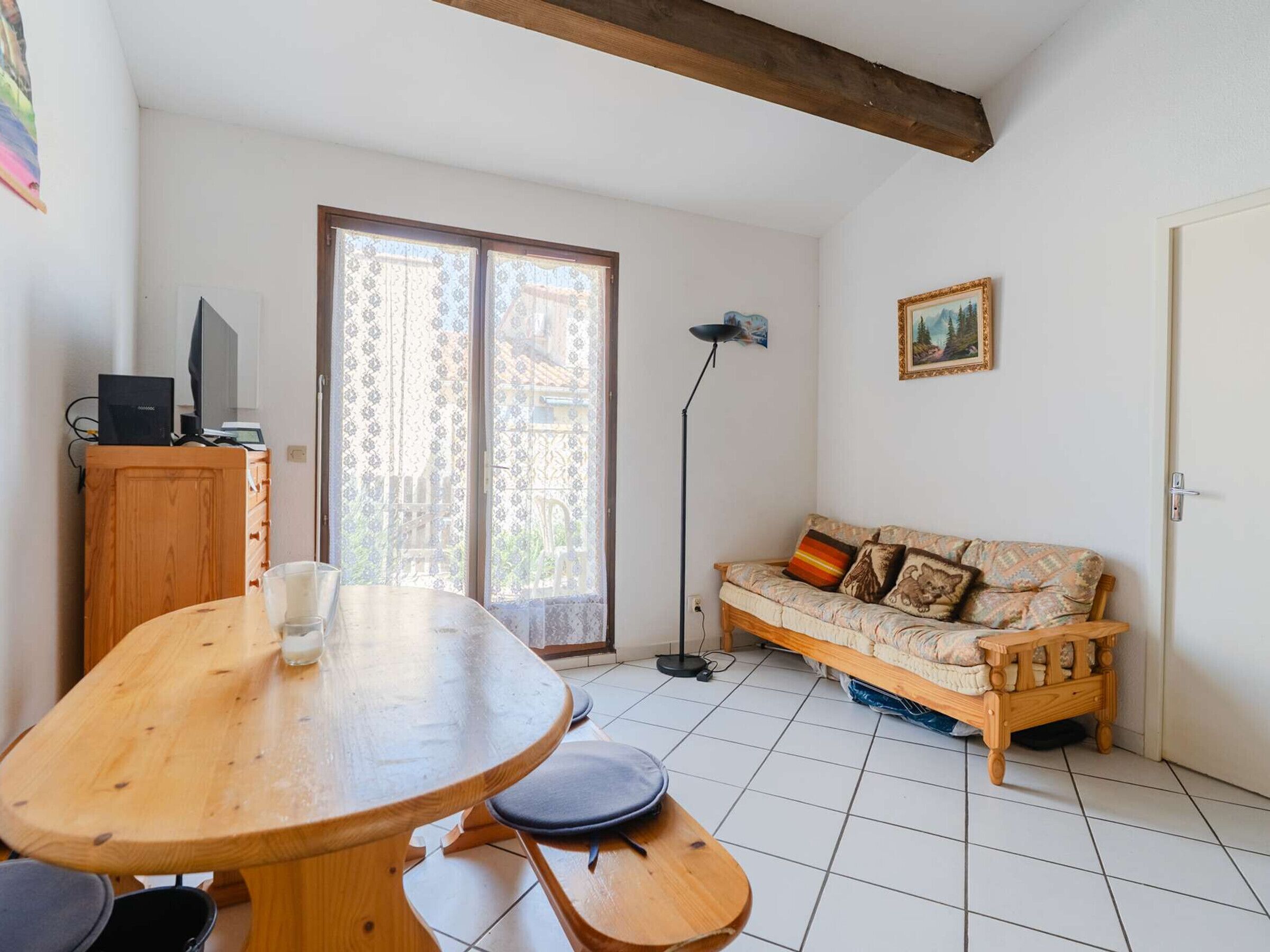 A room with a wooden table, a sofa, a floor lamp, and a painting on the wall.