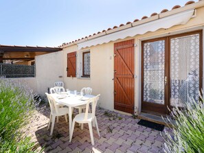 Eine Terrasse mit Tisch und Stühlen, eine Holztür und ein Fenster mit Rollläden.