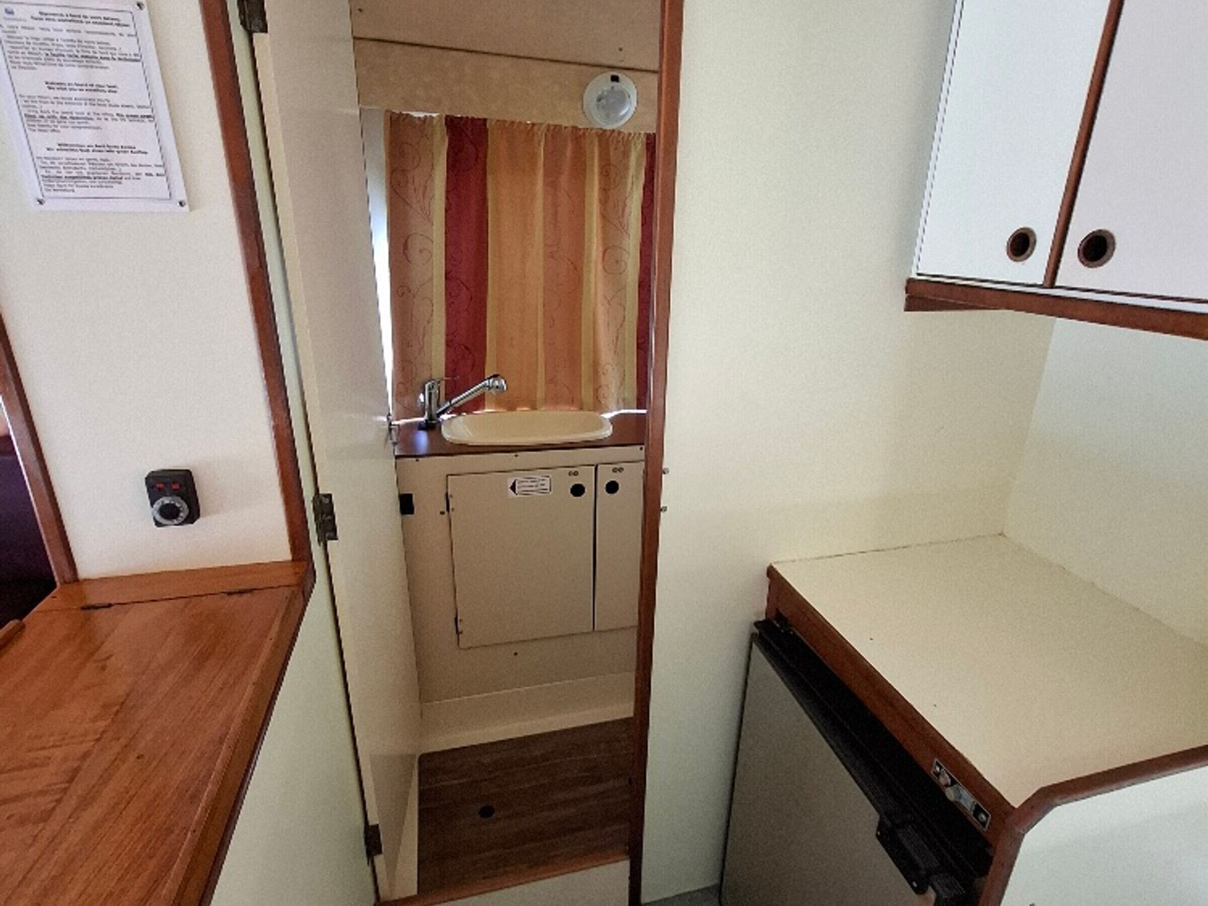 A compact kitchenette with a sink, a mirror, and a small cabinet.