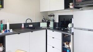 Een moderne keuken met witte kasten, een zwart aanrecht, een magnetron en een koelkast.