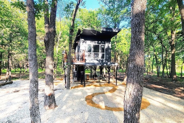 A treehouse structure elevated on stilts in a forested area.