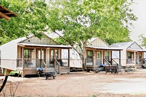 Eine Reihe von Mobilheimen mit Holzterrassen und Treppen, jedes mit Grill und Sitzgelegenheit im Freien.