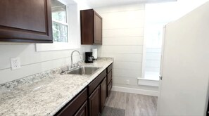 Une cuisine dotée de plans de travail en granit, d’un évier double, de meubles en bois foncé et d’une fenêtre offrant une vue agréable.
