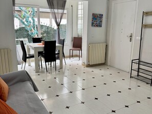 Ein Essbereich mit Tisch, Stühlen, einem Heizkörper, einer Tür und einem Wandregal.