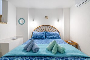 A bedroom with a bed, two wall-mounted lights, a round mirror, a small bedside table, and a wall-mounted air conditioner. - Bigflower’s House Sardinia: Sea View, Pool & Air Conditioning (Campulongu)
