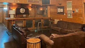 A wooden interior with a bar area, leather furniture, and a ceiling fan. - Reconnect by the Water: Tented Cabin Oasis for a Texas Lakeside Getaway (Cibolo)