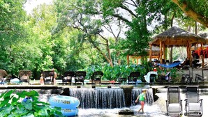A water feature with chairs and a gazebo in a lush, green setting. - Reconnect by the Water: Tented Cabin Oasis for a Texas Lakeside Getaway (Cibolo)