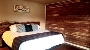 A bed with a plaid bedspread, a wooden headboard, and a sign above the bed. - Peaceful Paradise: Cabin Getaway with Unmatched River Views in Arkansas (Calico Rock)