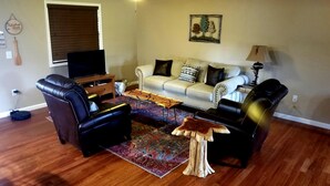 A living room with a sofa, two armchairs, a coffee table, a TV, and a lamp. - Peaceful Paradise: Cabin Getaway with Unmatched River Views in Arkansas (Calico Rock)