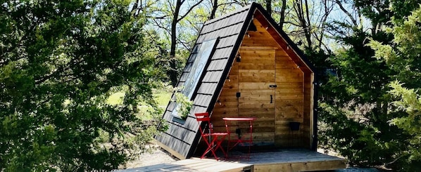 A wooden cabin with a sloped roof, a small porch, and a table with chairs.