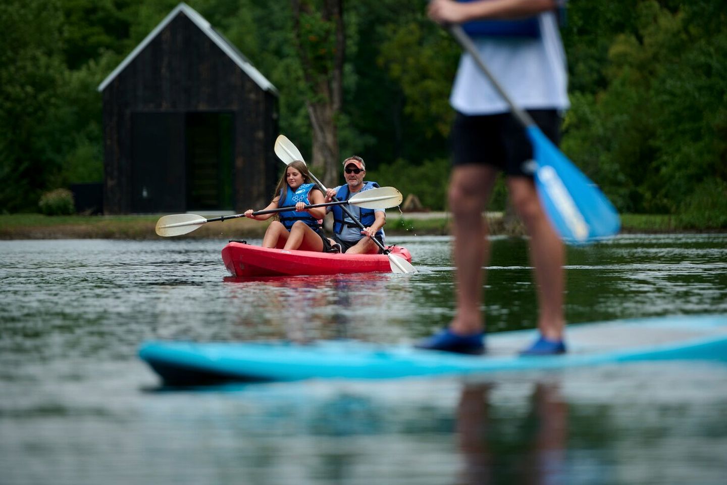Une personne est assise dans un kayak sur une étendue d’eau, avec un petit quai en arrière-plan.