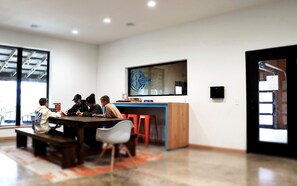 A modern meeting room with a large table, chairs, a bar area, and a large window.