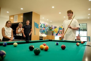 A pool table in a room with wooden cabinets and a colorful mural on the wall.