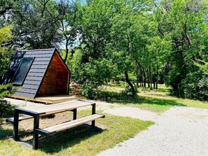 Una cabaña de madera con techo inclinado, una mesa de picnic y un camino de grava.