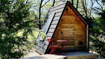 A wooden cabin with a sloped roof, a small porch, and a table with chairs.