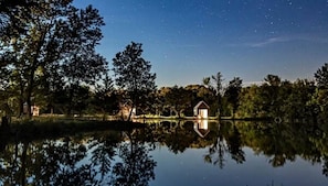 A lakeside view with a cabin and a small house reflecting on the water.
