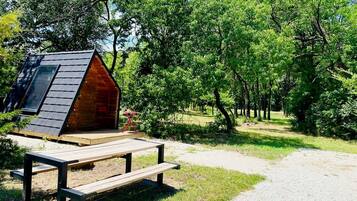 A wooden cabin with a sloped roof, a picnic table, and a gravel path.