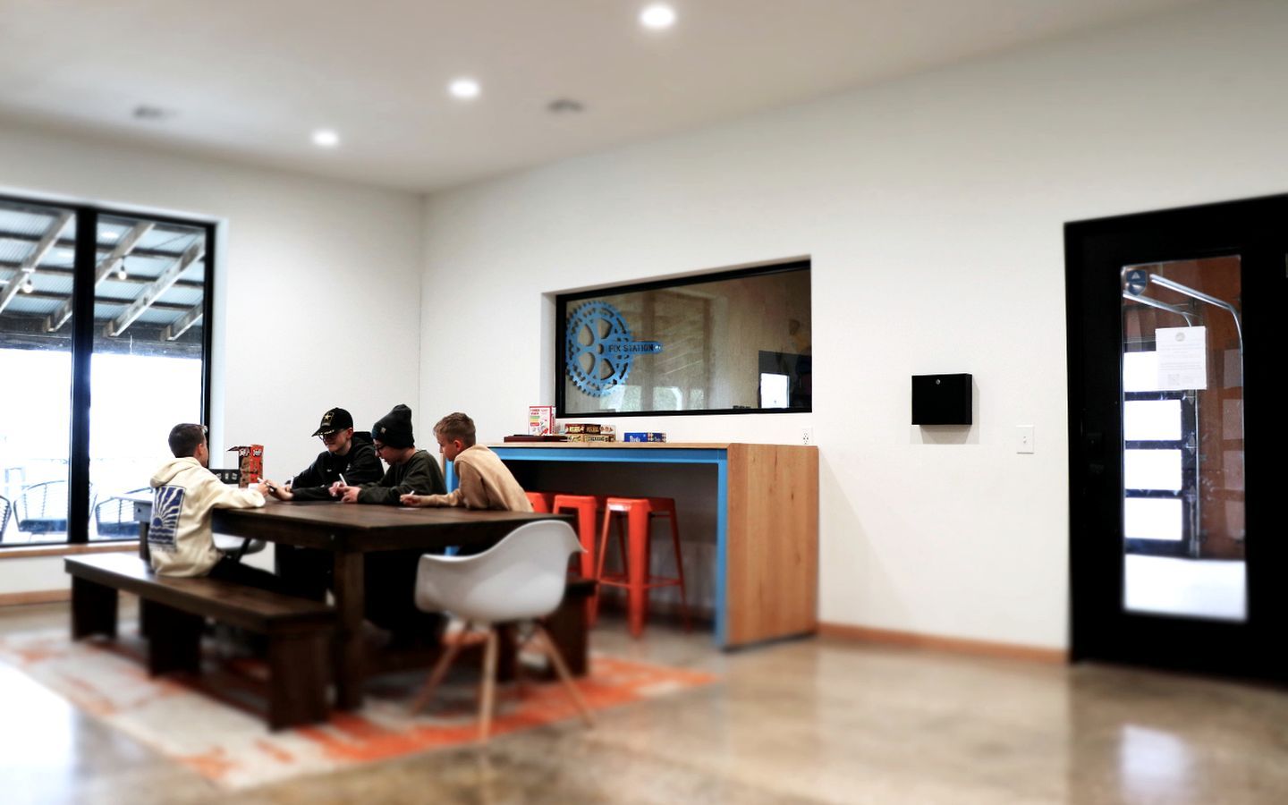 A modern meeting room with a large table, chairs, a bar area, and a large window.