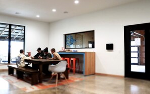 A modern meeting room with a large table, chairs, a bar area, and a large window.