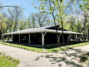 A covered outdoor pavilion with a gravel path leading to it, surrounded by trees.