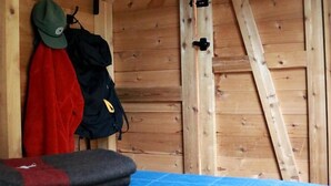 A wooden room with a sloped ceiling, a bed with a blue mattress, and a door with a black handle. - Charming A-Frame Cabin Experience with Campfire Vibes in Humboldt, Kansas (Humboldt)