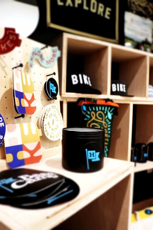 Une exposition de divers articles, notamment une tasse noire ornée d’un logo, des gants colorés et un panneau sur lequel on peut lire « EXPLORE ».