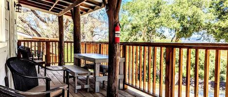 A covered outdoor deck with wooden furniture and a view of a river.
