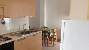 A kitchen with wooden cabinets, a sink, a stove, and a dining area with a table and chairs. - Vacation house located in quiet hillside area with sea view and swimming pool (Vieste)