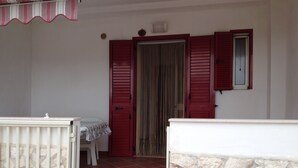 A room with a stone wall, a white door, and a window with red shutters. - Vacation house located in quiet hillside area with sea view and swimming pool (Vieste)