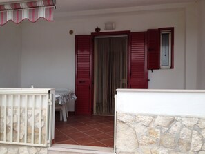 A room with a stone wall, a white door, and a window with red shutters. - Vacation house located in quiet hillside area with sea view and swimming pool (Vieste)