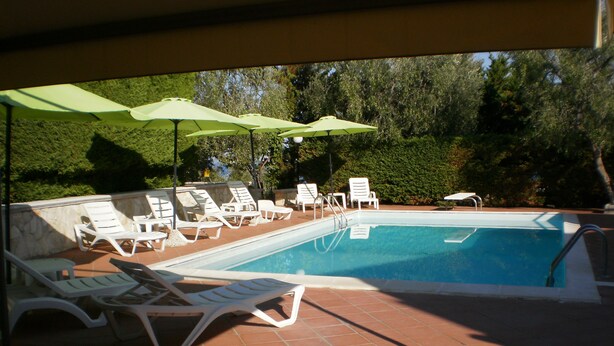 A swimming pool with lounge chairs and umbrellas. - Vacation house located in quiet hillside area with sea view and swimming pool (Vieste)