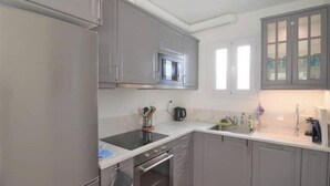 Una cocina con gabinetes grises, un microondas, una estufa y un lavamanos.