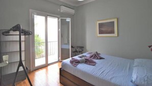 Un dormitorio con cama, armario, puerta que da a un balcón y un cuadro en la pared.